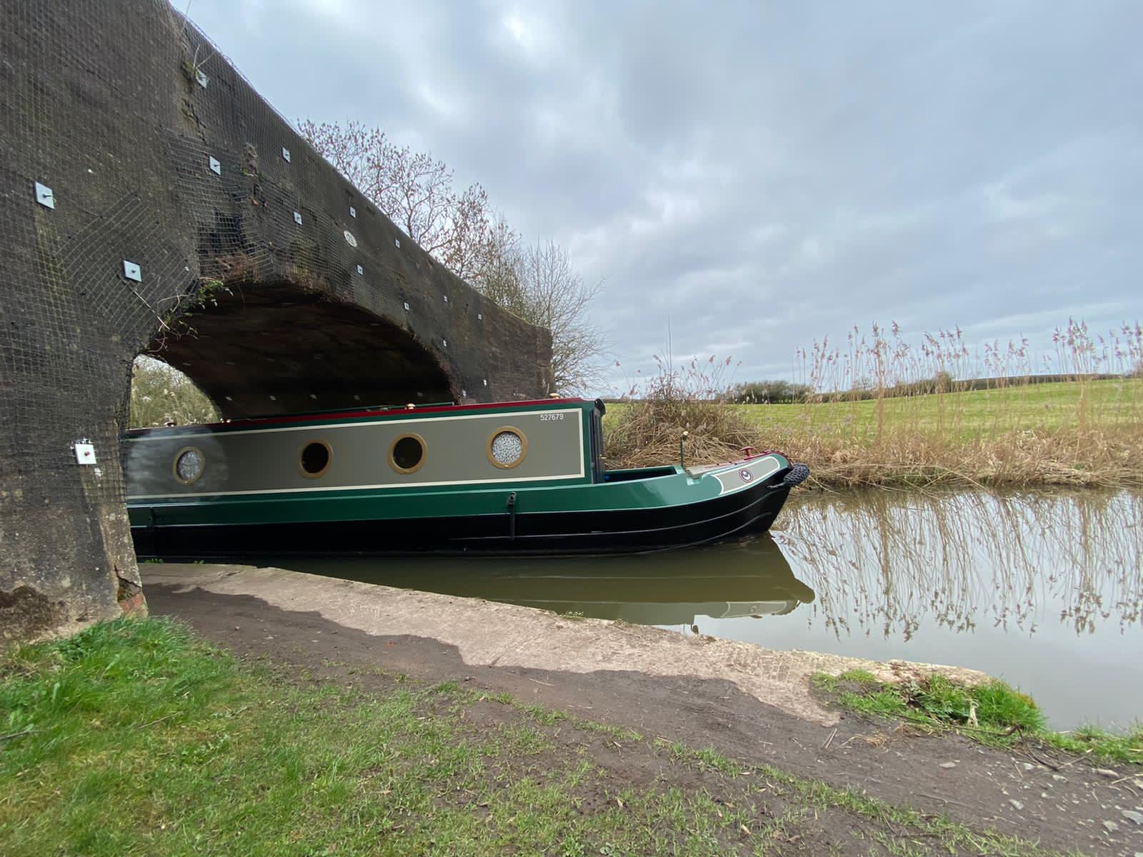 new narrowboat build passing under canal bridge