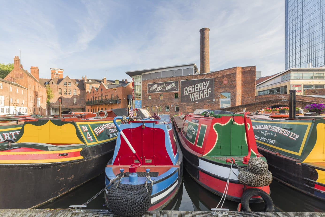 5 differently coloured canal boats moored side-by-side at Gas Street Basin